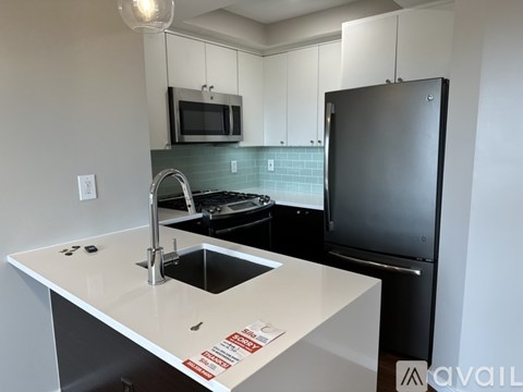 A kitchen with a black refrigerator and a white counter top.