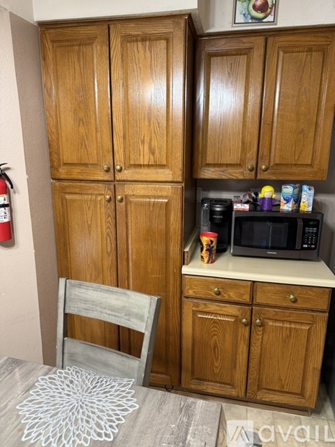A kitchen with wooden cabinets and a white doily on the floor.
