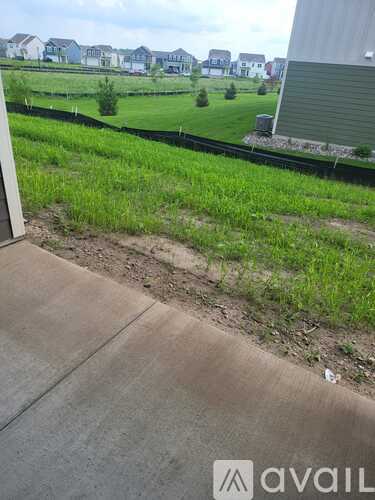 A grassy area with a sidewalk and a building in the background.