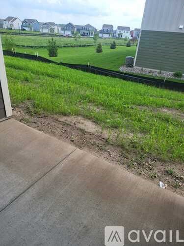 A grassy area with a sidewalk and a building in the background.