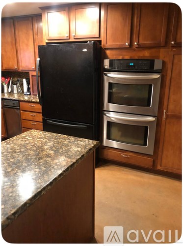 A kitchen with a black fridge and stainless steel ovens.