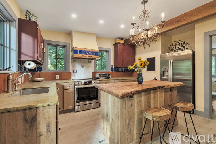 A kitchen with a wooden island and a chandelier.