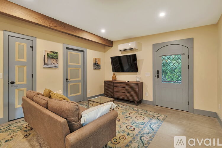 A living room with a brown couch and a flat screen TV mounted on the wall.