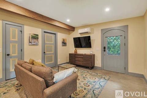 A living room with a brown couch and a flat screen TV mounted on the wall.