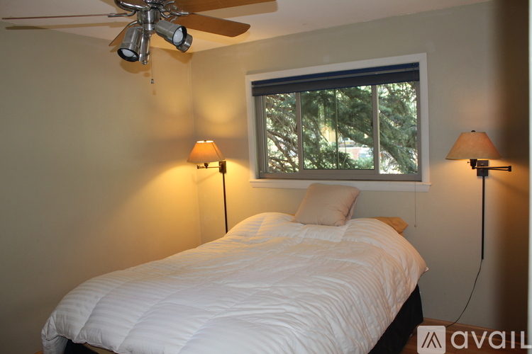 A bedroom with a white bed and two lamps.