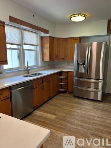 A kitchen with wooden cabinets and a stainless steel refrigerator.