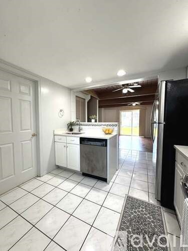 A kitchen with white cabinets and a black fridge.