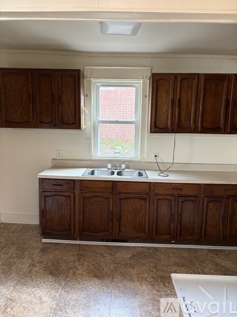 A kitchen with brown cabinets and a window.