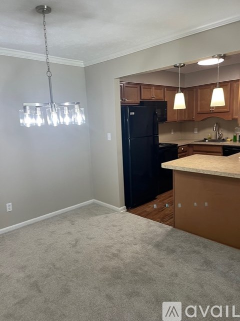 A kitchen with a black refrigerator and wooden cabinets.