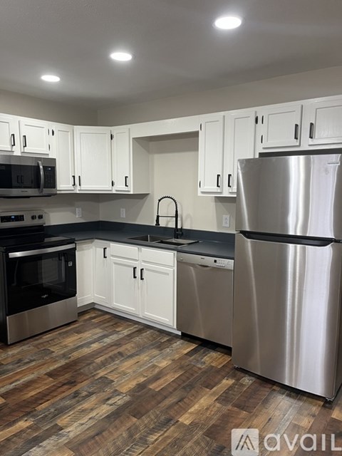 A kitchen with white cabinets and a wooden floor.