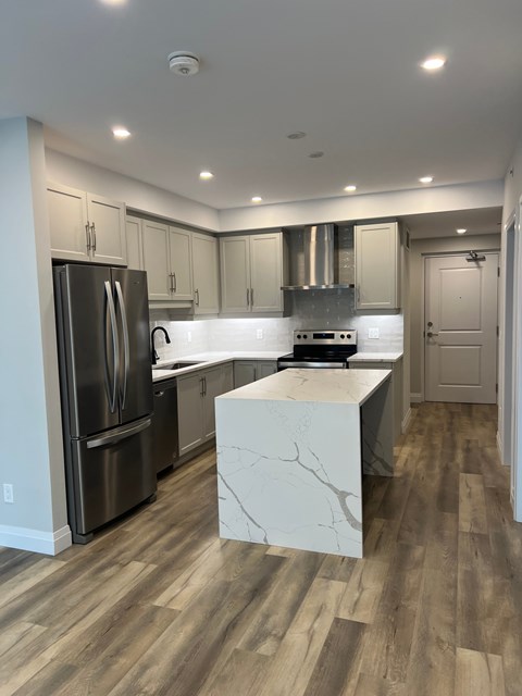 A kitchen with a refrigerator, stove, and cabinets.