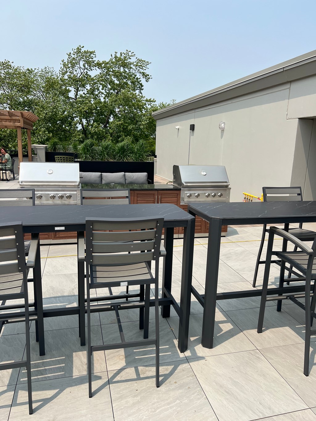 A table and chairs set up on a patio with a grill in the background.