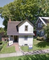 A white house with a brown roof and a small front yard.