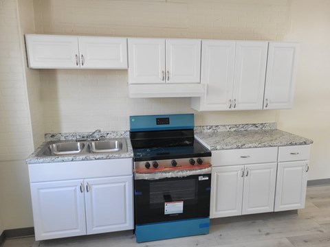 A kitchen with white cabinets and a blue oven.