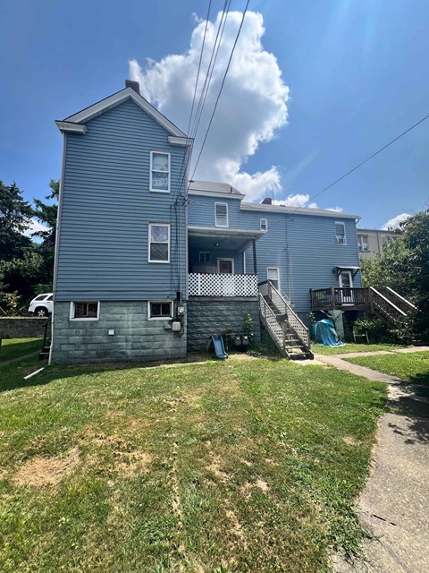 A two-story house with a blue exterior and a white car parked in the driveway.