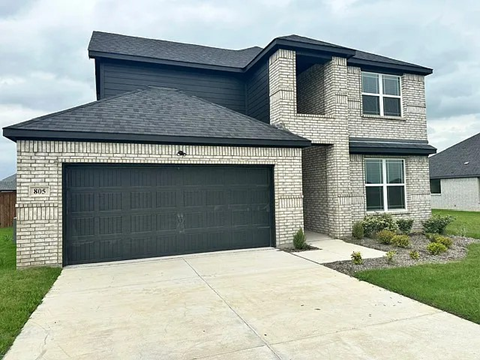 A two-story house with a garage door and a driveway.