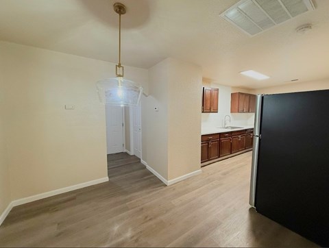 A kitchen area with a black refrigerator and wooden cabinets.