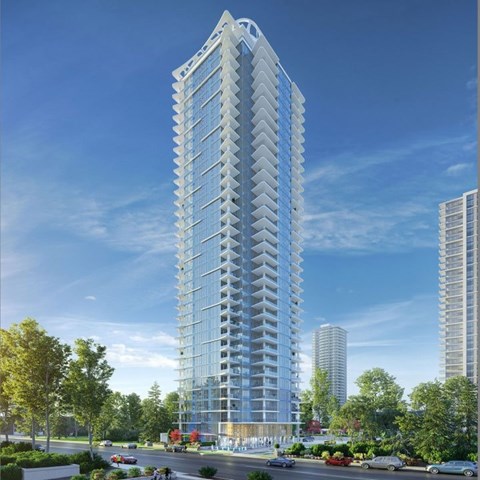A tall, modern glass building stands in a city setting with trees and a street in front.