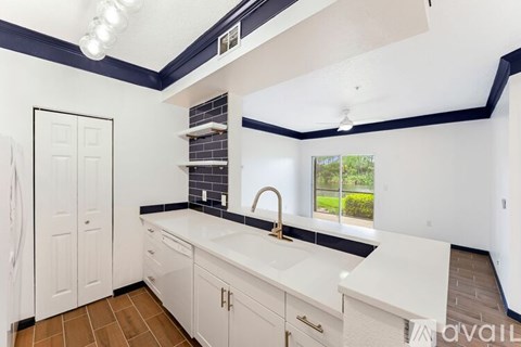 A kitchen with white cabinets and a black and white tile backsplash.