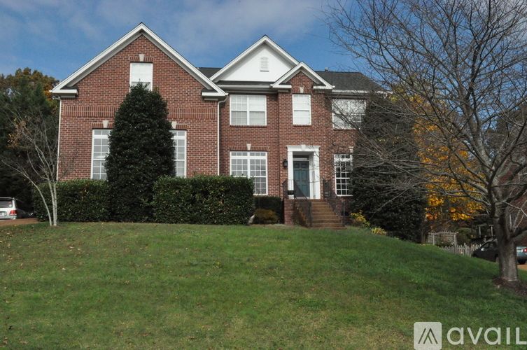 A red brick house with a white trim and a large front yard.