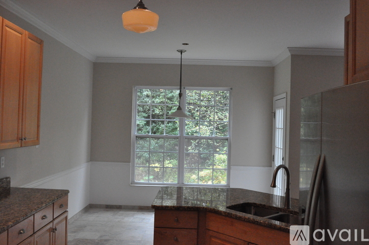 A kitchen with wooden cabinets and a window with a view of trees.