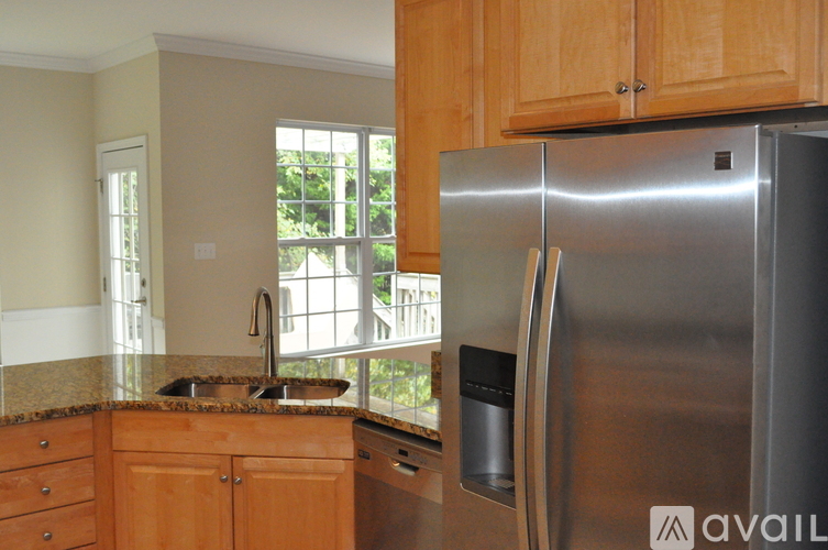 A kitchen with a stainless steel refrigerator and wooden cabinets.