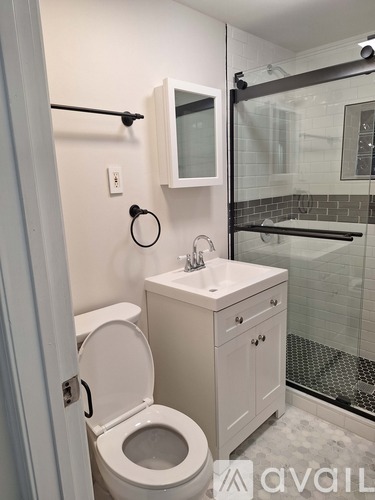 A room with wooden floors and white walls, with a door open to another room.