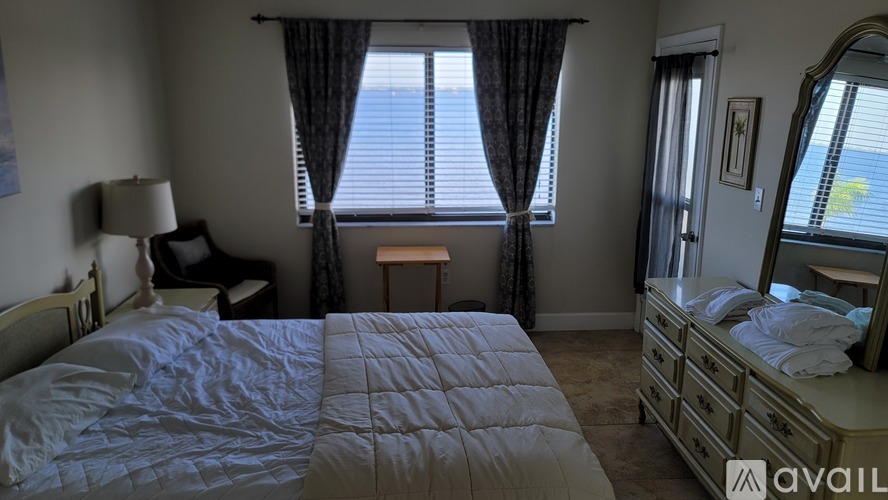 A bedroom with a large bed and a window with curtains.