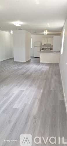 A spacious room with a kitchen area in the background.