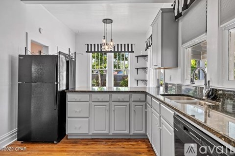 A kitchen with a black refrigerator and wooden floors.