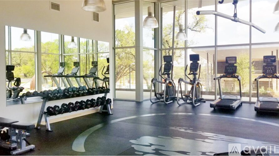 A gym with a row of dumbbells and exercise machines.