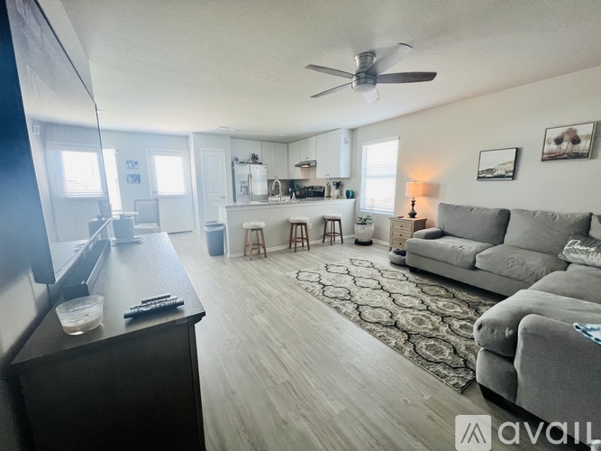 A living room with a grey couch and a ceiling fan.