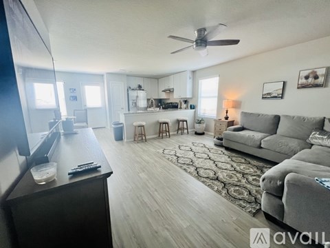 A living room with a grey couch and a ceiling fan.