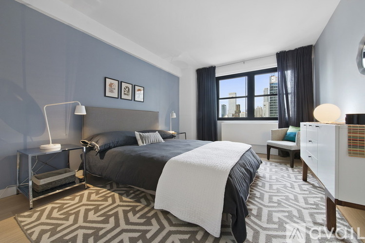 A bedroom with a large bed and a window overlooking a cityscape.