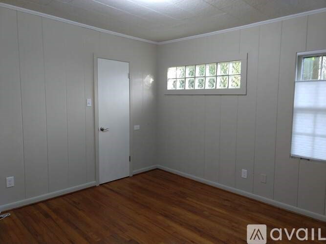 A room with wooden floors and white walls, with a window on the right side.