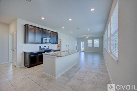 A kitchen with black cabinets and a white island.