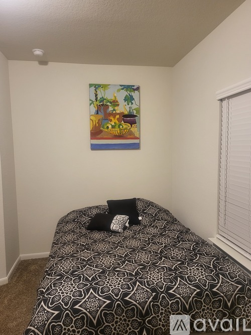 A bedroom with a bed and a painting on the wall.