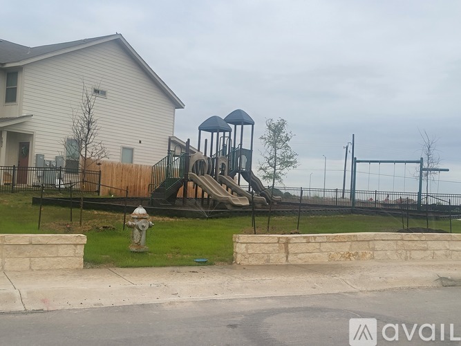 A playground with a slide and a fire hydrant in front of a house.