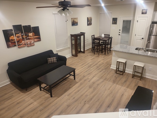 A living room with a black couch and a dining table with chairs.