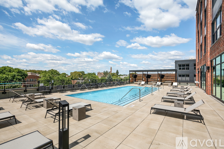 A pool area with sun loungers and a building in the background.