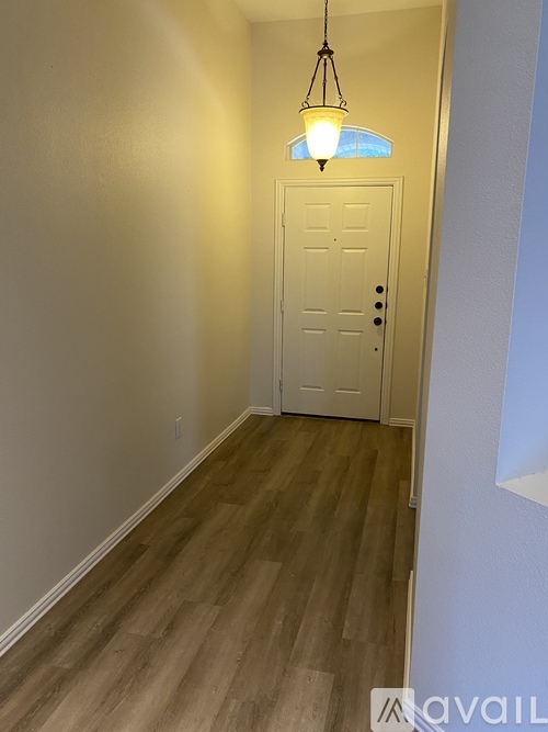 A hallway with a white door and a light hanging from the ceiling.