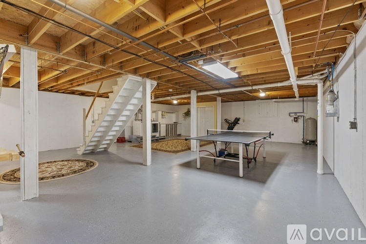 A spacious room with a ping pong table and a staircase.