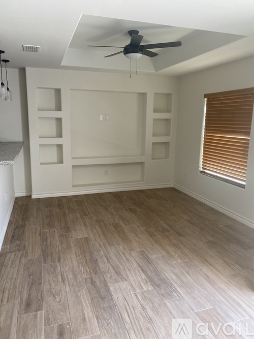 A room with a ceiling fan and wooden flooring.
