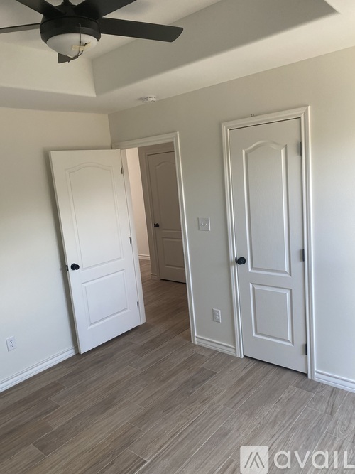 A room with a ceiling fan and three doors.