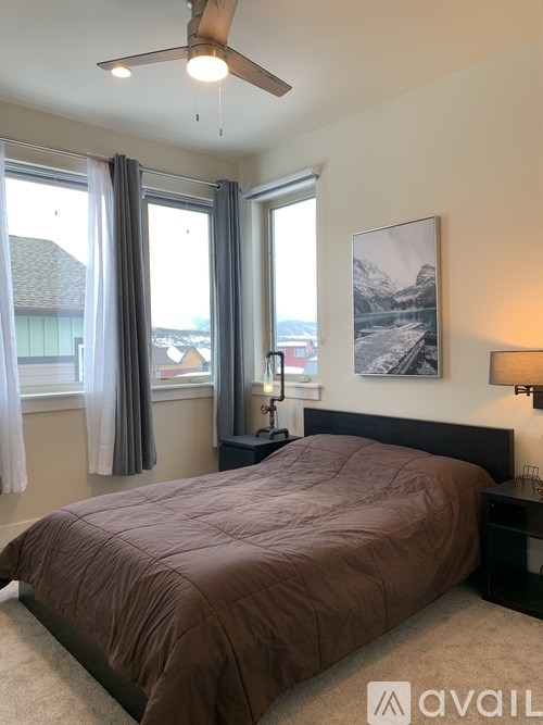A bedroom with a large bed and a mountain painting on the wall.
