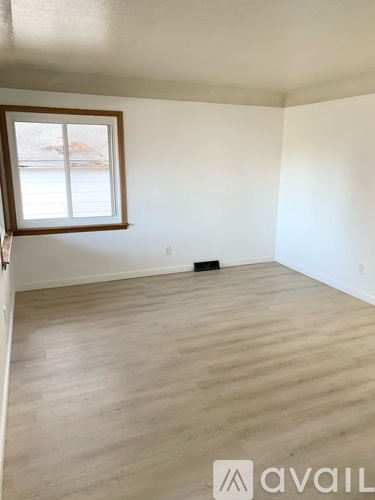 A room with wooden flooring and a window.