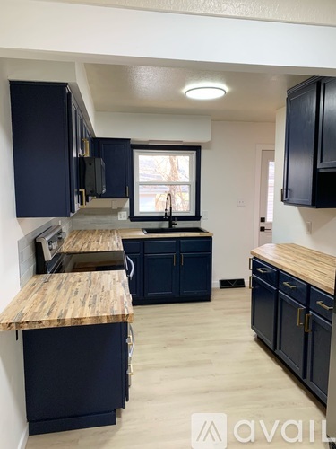 A kitchen with dark blue cabinets and a wooden countertop.