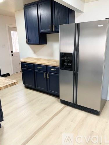 A kitchen with a stainless steel refrigerator and wooden countertops.