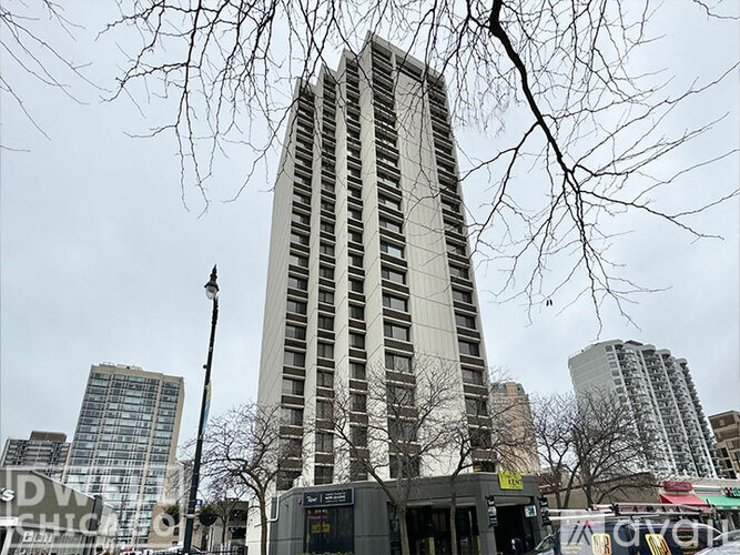 A tall building stands in front of a bus stop.