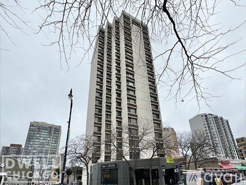 A tall building stands in front of a bus stop.